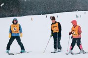 ガイドサポーターから教わりながら滑走する参加者（中央）＝立山山麓スキー場極楽坂エリア