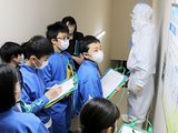 製造工場内を回り、衛生管理を徹底するクリーンウエアを見学する児童＝ウーケ
