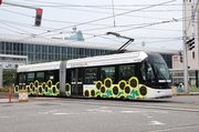 富山もようの新柄｢ひまわり｣がラッピングされた車両＝富山駅前