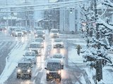 降りしきる雪の中、通勤の車で混み合う道路＝２３日午前７時１０分ごろ、富山市清水町