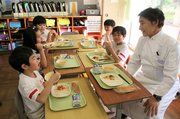工藤さん（右）と話を楽しみながら給食を味わう児童＝新湊放生津小学校