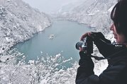雪化粧した山々に囲まれた川面を進む遊覧船。国道からカメラを構える写真愛好家の姿も見られた＝庄川峡