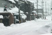 車庫の雪を下ろしたり、道を除雪したりする住民＝６日午後３時ごろ、魚津市上村木（椎名哲平撮影）