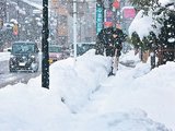 雪が降る中、積雪のため狭くなった歩道を歩く人＝２１日午後４時１５分ごろ、砺波市新富町