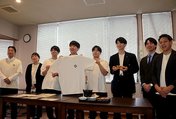 ウニの殻を使って染色したＴシャツを披露する氷見高校生ら＝氷見市北大町のひみ番屋街