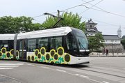 富山城の前を通過するラッピング電車＝富山市大手町