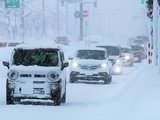 路肩に胸の高さまで雪が積もった県道を走る車＝６日午前７時４０分ごろ、魚津市印田