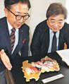 高岡銅器の技術で再現したすしのオブジェを紹介する竹中理事長（左）ら