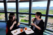 砺波平野や立山連峰が望める展望フロアでスイーツを味わい、笑顔を見せる来場者