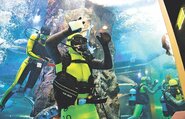 スポンジで丁寧に汚れを落とす滑川高校生のダイバー＝魚津水族館