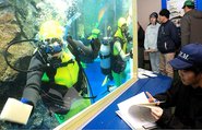 隅々まで水槽を磨く滑川高校生のダイバー＝魚津水族館