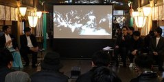 完成した映像作品を上映しながらコンセプトを説明する見角さん（右から３人目）＝放生津八幡宮
