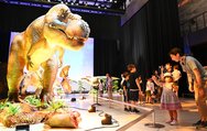 ティラノサウルスなど実物大の恐竜ロボットを見る家族連れ＝氷見市芸術文化館