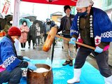 傘を差した来場者が見守る中、餅つきをする関係者＝南砺市福野