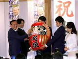 家族が持つだるまに笑顔で目を入れる藤井氏