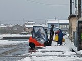 雪が降り始めた中、漁港周辺を除雪する男性＝８日午前９時ごろ、黒部市生地中区
