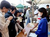 福野小５年生が考案したサトイモ料理を試食する来場者（左側）