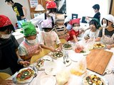 未利用魚のすり身を使ったピザを作る氷見高生と十二町小の児童たち＝ウルキビレッジ