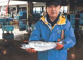 今年出荷した氷見サーモンを手にする荻野組合長。来年はより大きな魚体を目指す＝５月、氷見魚市場