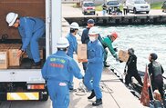 物資輸送訓練で、自衛隊のゴムボートで届けられた物資をトラックに積み込む参加者=入善漁港