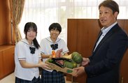 上田実行委員長（右）から野菜を受け取る野阪さん（左）と樋口さん＝高岡龍谷高校