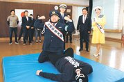 交通安全大使に任命され、技を決めるマサ選手と見守る佐藤さん
