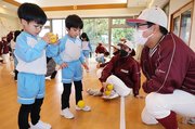 園児にボールのキャッチについて指導する部員