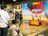 気球に乗ったように見える作品を楽しむ来場者たち＝県高岡文化ホール