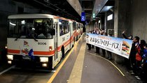 横断幕を掲げた社員らに見守られ、大観峰に向けて出発するトロリーバスの最終便＝室堂駅