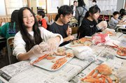 笑顔でカニをむく児童＝新湊放生津小学校