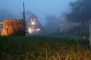 田んぼにはさ掛けが設けられ、秋の装いとなった集落でライトアップされた合掌造り家屋＝１２日午後６時１０分ごろ、南砺市相倉