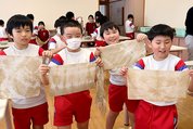 ギフチョウのふんで染めた絹を手にする児童＝南砺市城端小学校