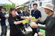 市原さん（右）から良い実の見分け方などを教わる「あいの宿・氷見」の叶会長（左から２人目）ら＝いちはらメロン農園