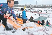 スタンドやピッチを除雪するサポーターら＝県総合運動公園陸上競技場